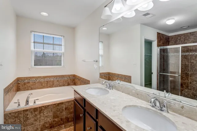 a bathroom with a granite countertop tub a double vanity sink and a large mirror