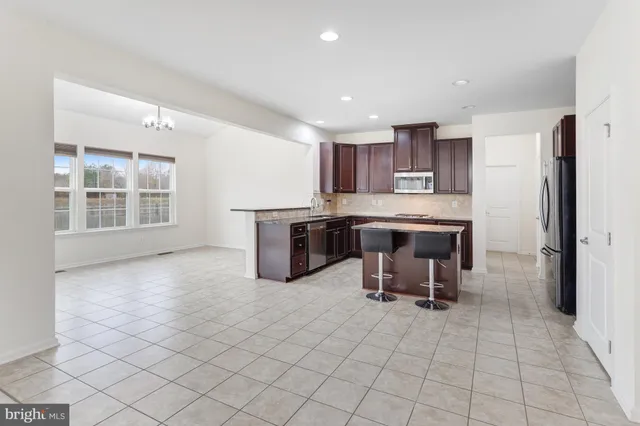 a kitchen with kitchen island granite countertop a sink cabinets and stainless steel appliances