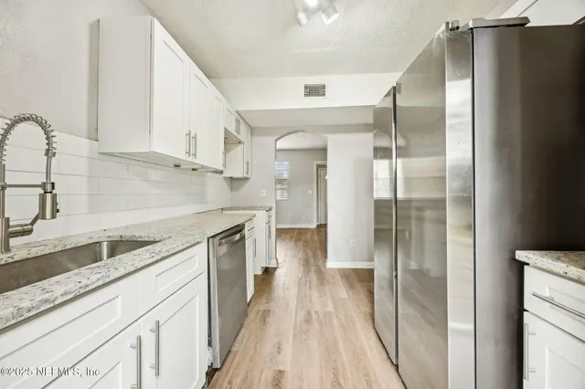 an empty room with wooden floor and a sink