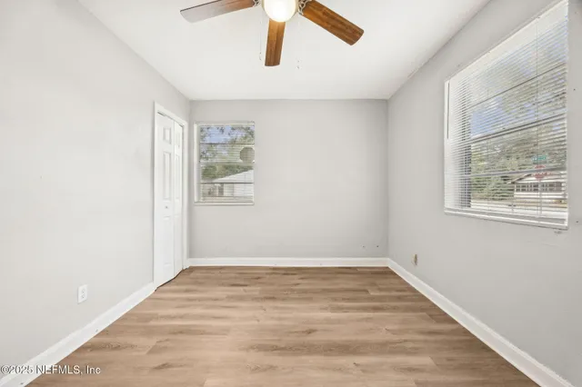 an empty room with wooden floor closet and fan