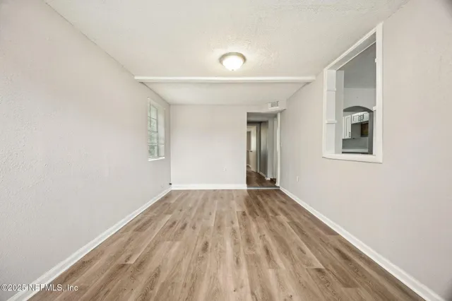 a view of an empty room with wooden floor and a window