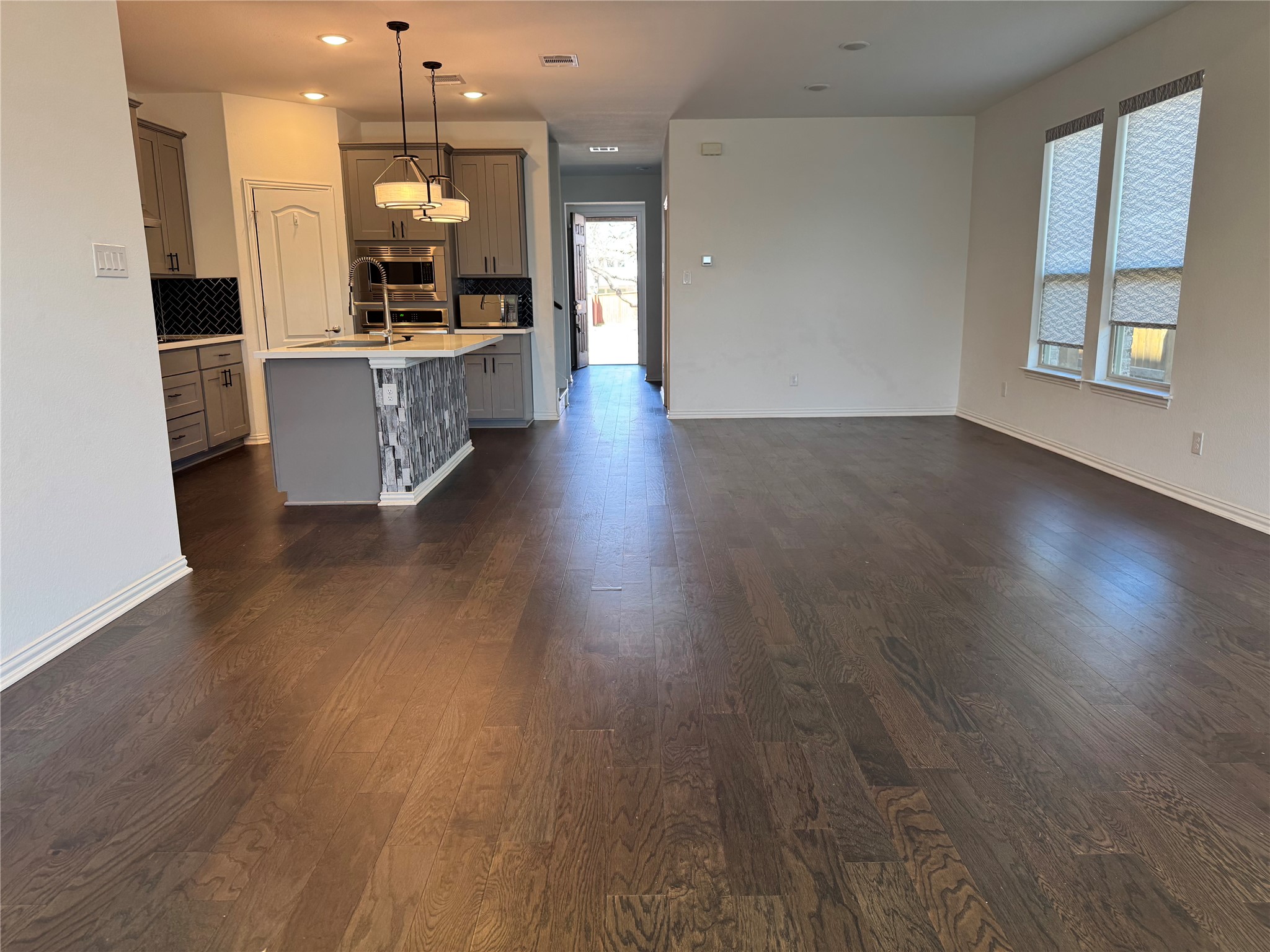 623 Pheasant Hill Lane Georgetown, TX 78628 - Photo 16 of 17 Kitchen featuring gray cabinetry, open floor plan, pendant lighting, a kitchen island with sink, and decorative backsplash