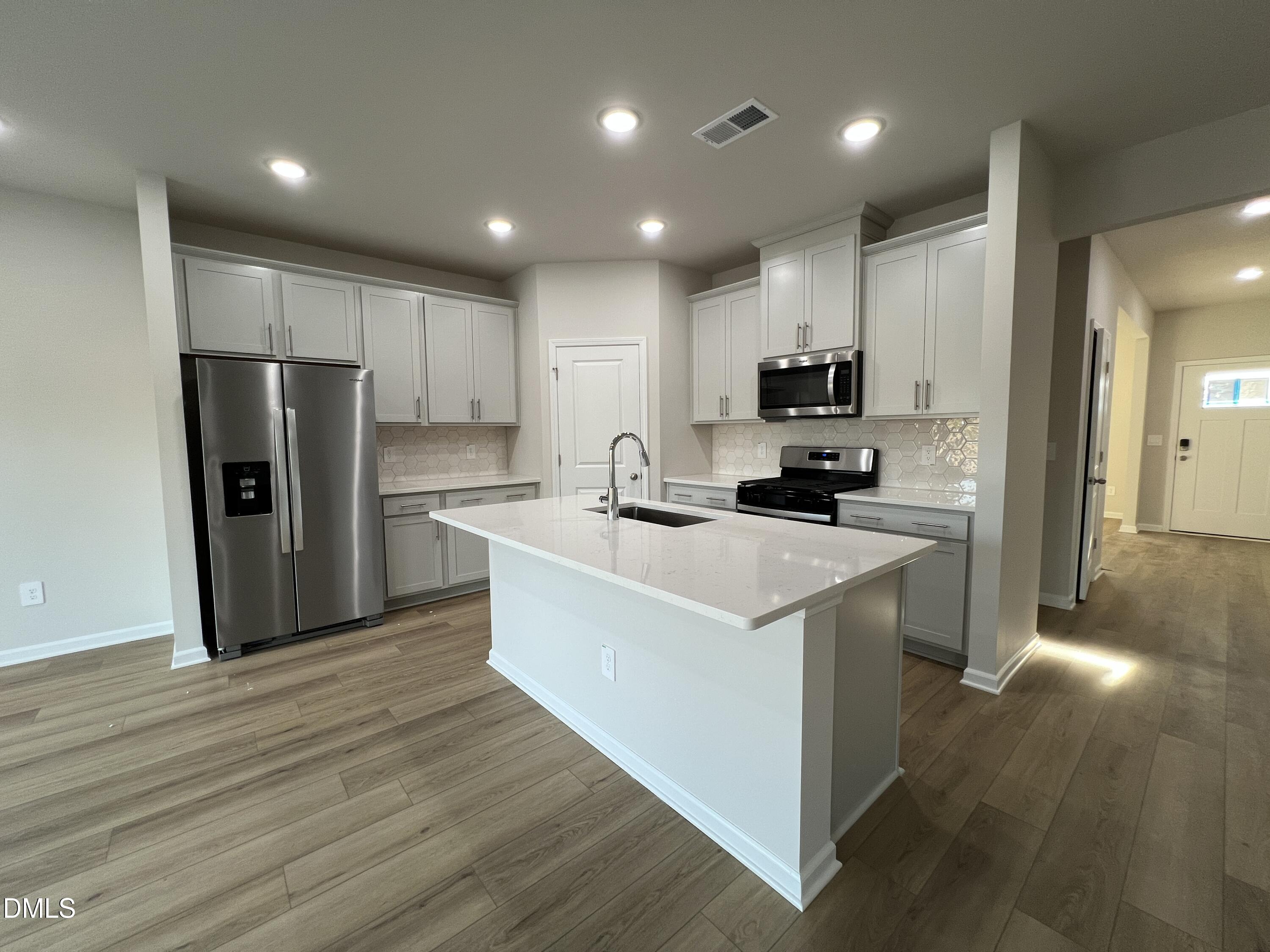 212 Thistle Patch Place Angier, NC 27501 - Photo 6 of 32 a kitchen with kitchen island a refrigerator and a stove top oven
