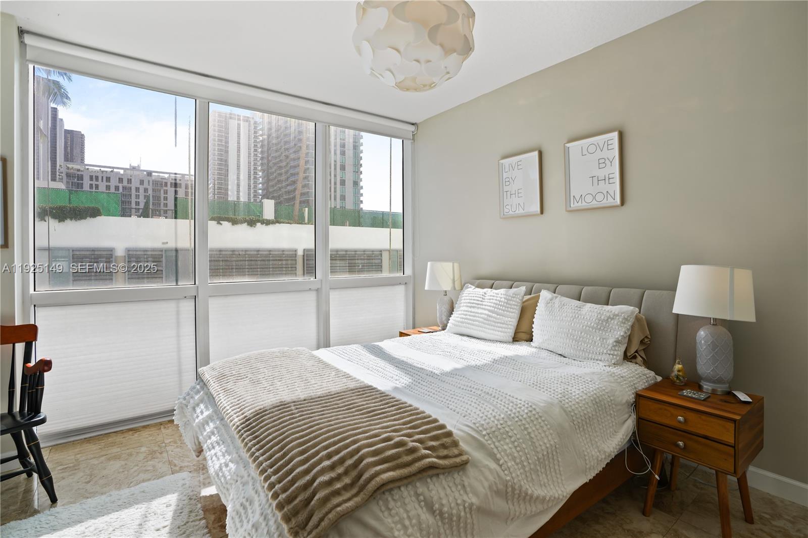 480 Northeast 30th Street, Unit 703 Miami, FL 33137 - Photo 16 of 31 a bedroom with a bed and a lamp next to a large window