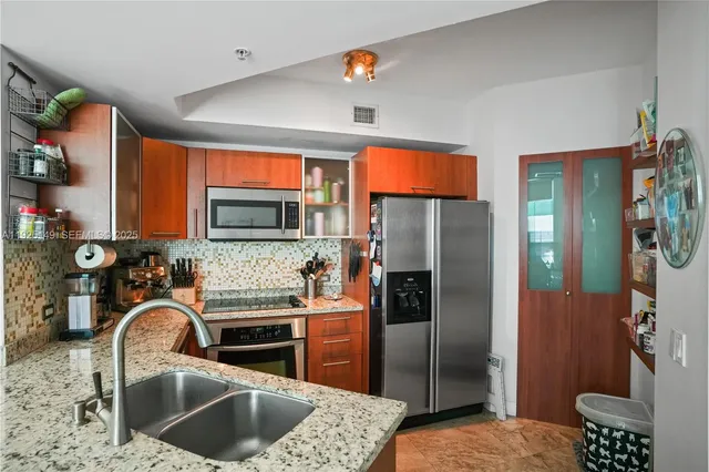 a kitchen with stainless steel appliances granite countertop a refrigerator and a sink