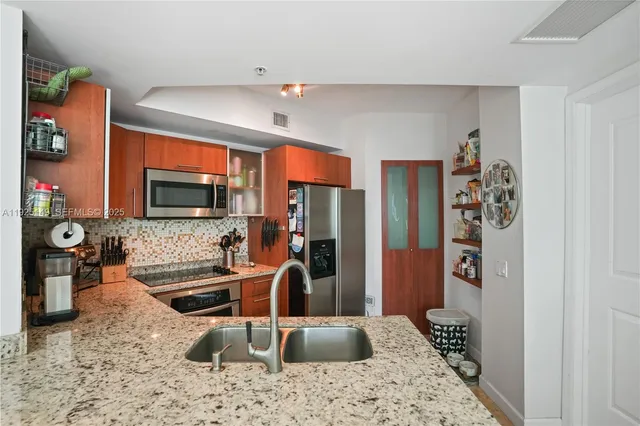 a kitchen with stainless steel appliances kitchen island granite countertop a refrigerator and a sink