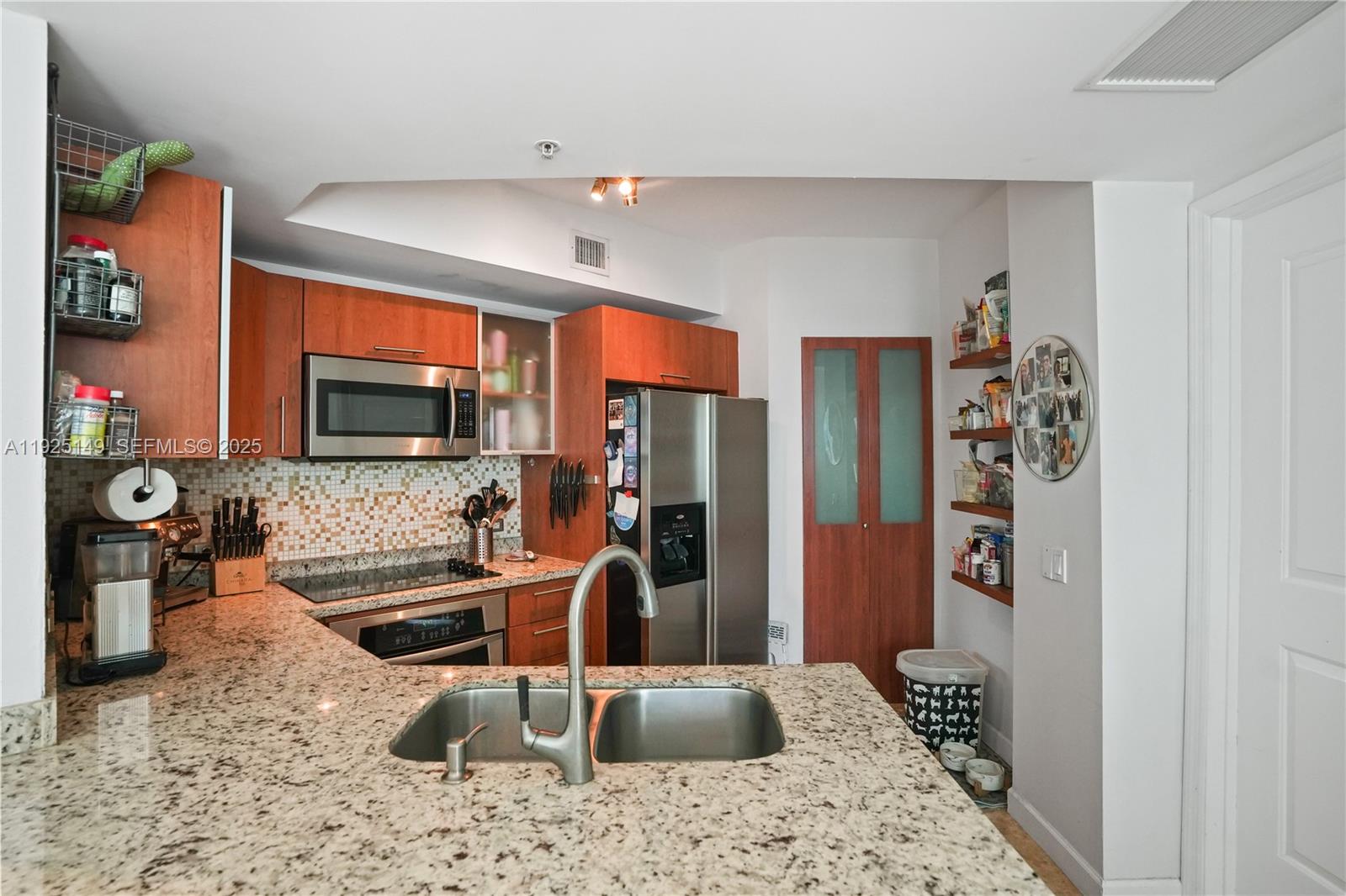 480 Northeast 30th Street, Unit 703 Miami, FL 33137 - Photo 9 of 31 a kitchen with stainless steel appliances kitchen island granite countertop a refrigerator and a sink