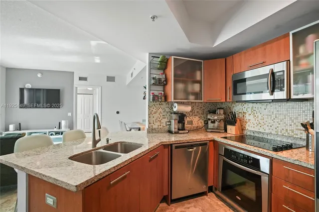 a kitchen with stainless steel appliances granite countertop a sink stove microwave and refrigerator