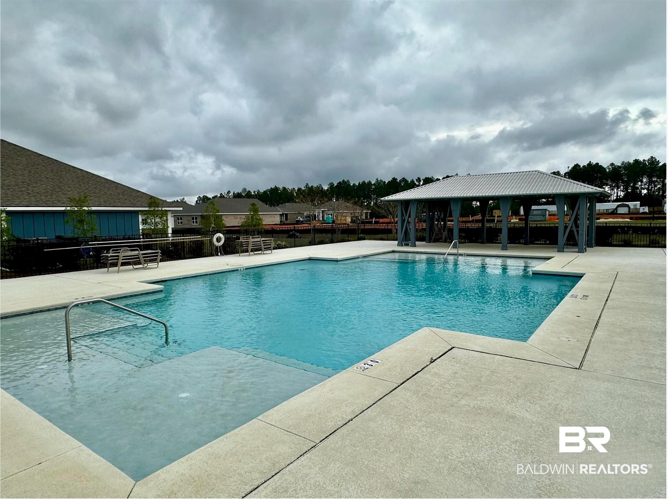 1040 Hayward Loop Foley, AL 36535 - Photo 28 of 35 Expansive swimming pool featuring an integrated shallow wading area with handrails, surrounded by a broad concrete deck