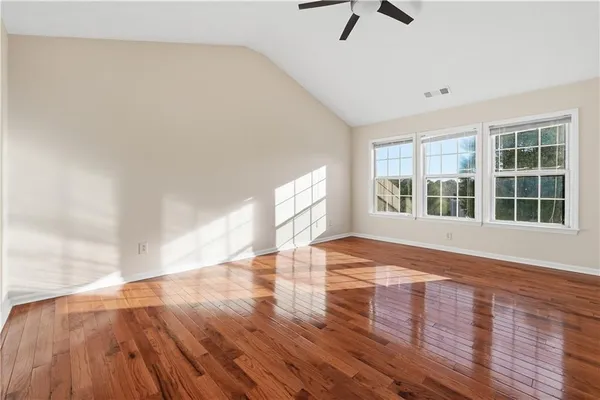 a view of an empty room with window and wooden floor