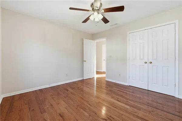 an empty room with wooden floor a ceiling fan and closet
