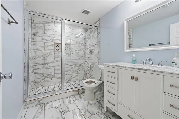 a bathroom with a granite countertop sink a toilet and shower