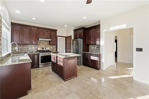a kitchen with stainless steel appliances granite countertop a stove top oven a refrigerator and a sink