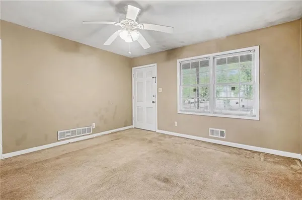 an empty room with windows and fan