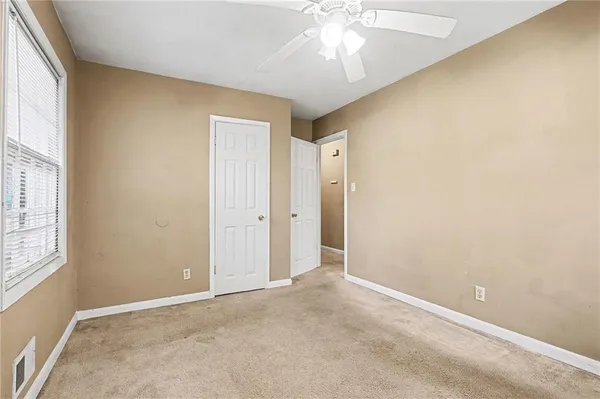 an empty room with a chandelier fan and windows
