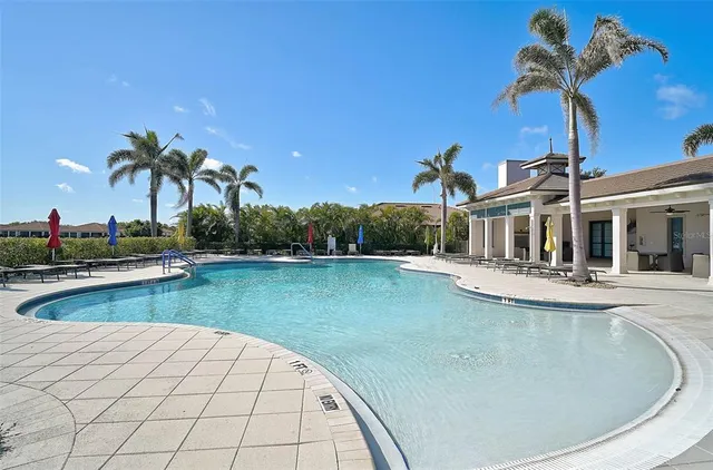 a view of a swimming pool with a yard and palm trees