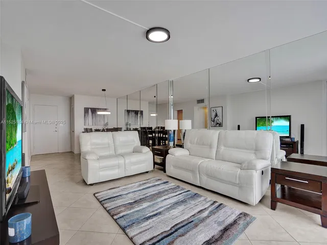 a living room with furniture a flat screen tv and a floor to ceiling window
