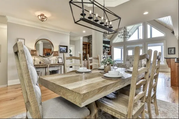 a dining room with wooden floor a chandelier a wooden table and chairs