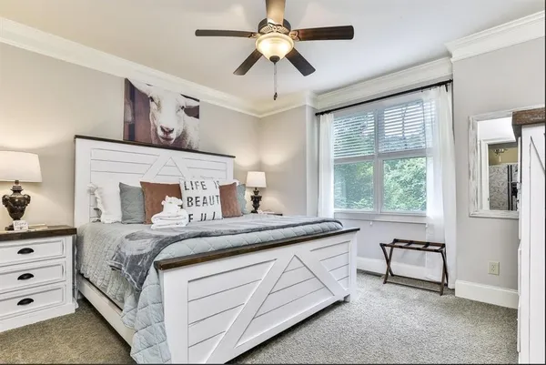 a bedroom with a large bed and a chandelier fan