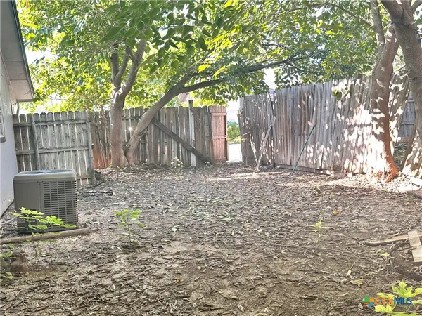 a view of a house with a small yard and large tree