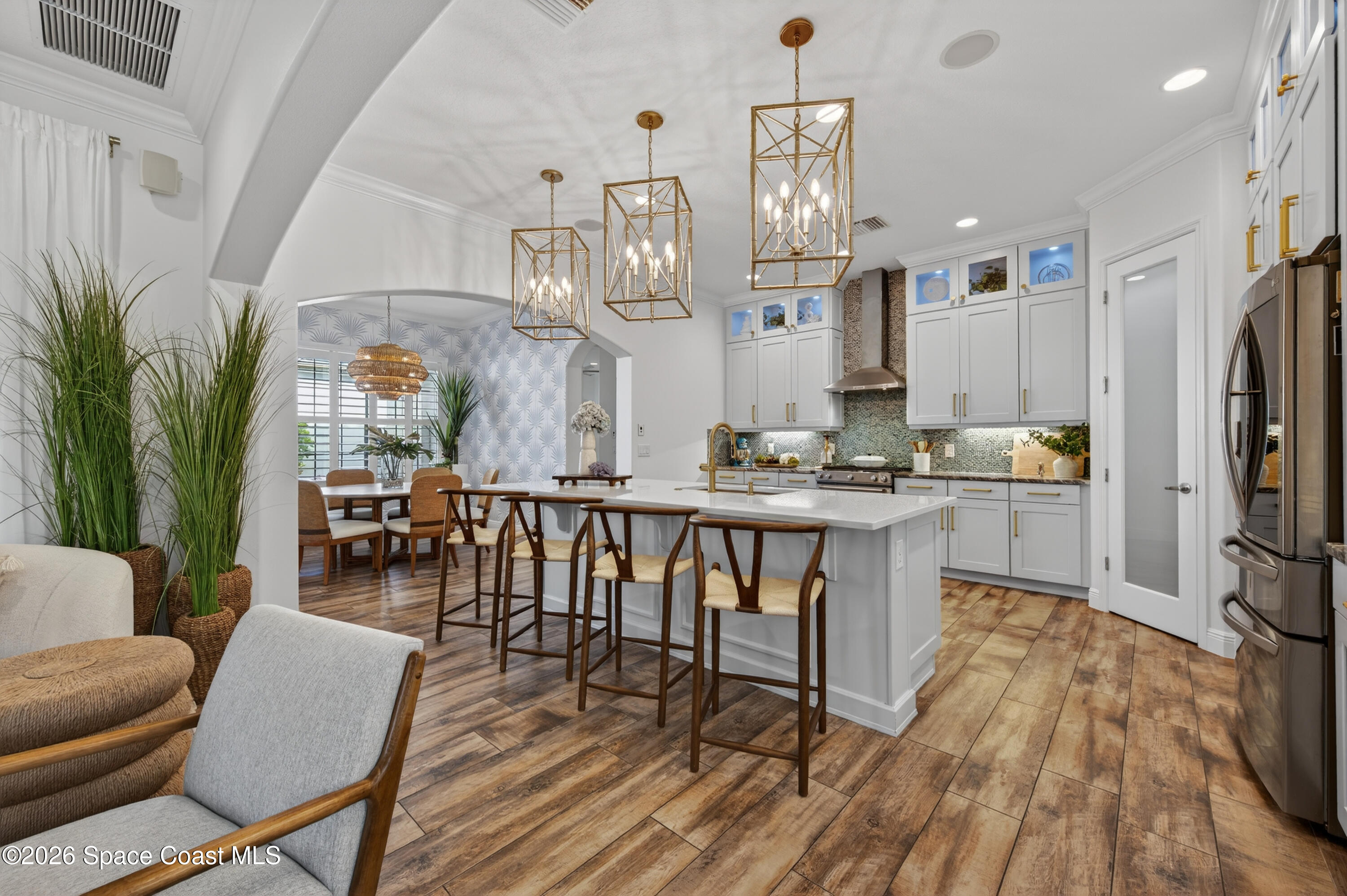 2343 Rodina Drive Melbourne, FL 32940 - Photo 65 of 72 a kitchen with stainless steel appliances kitchen island granite countertop a refrigerator a stove a microwave oven a dining table and chairs with wooden floor