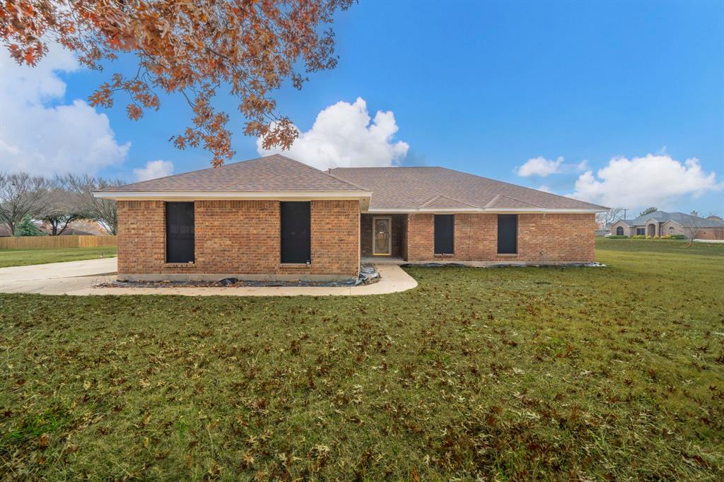 Back of house featuring a lawn, brick siding, and a shingled roof