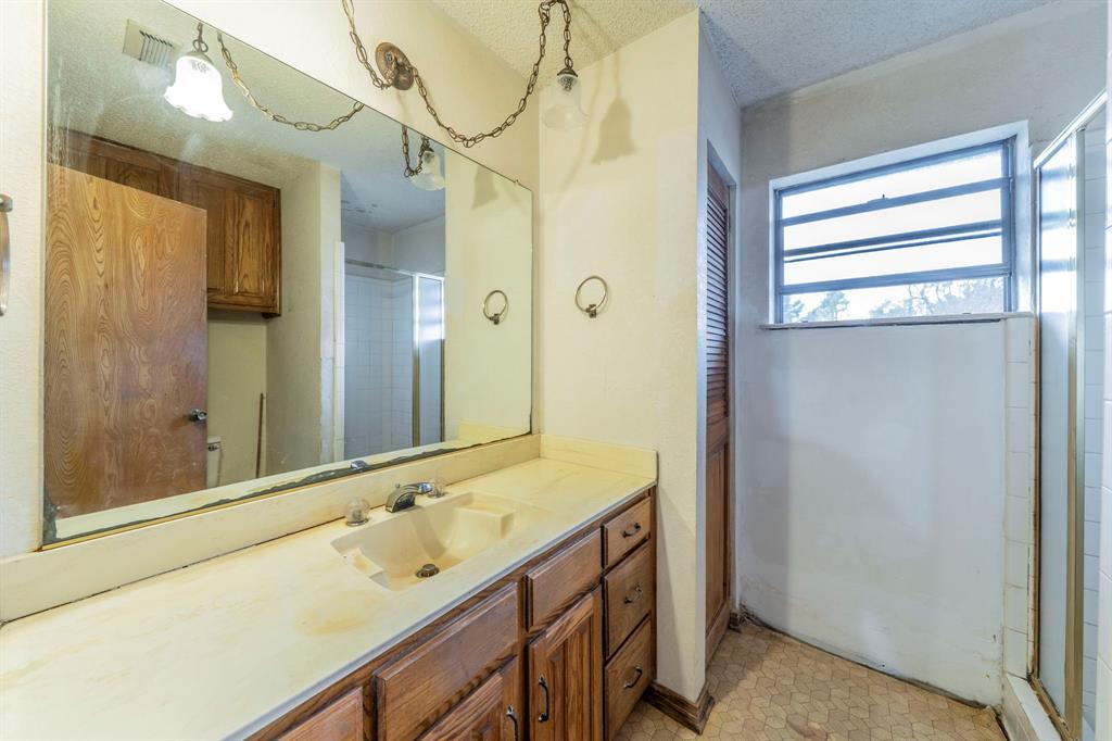 1202 Panorama Loop Waxahachie, TX 75165 - Photo 13 of 26 Full bath with vanity, a textured ceiling, light flooring, and a shower with door