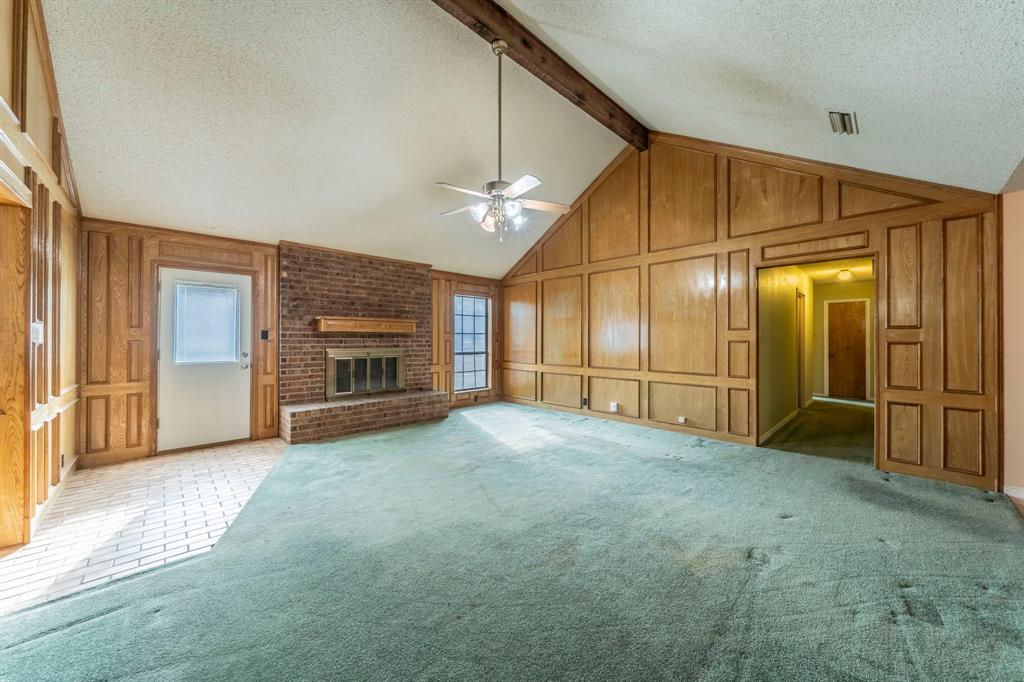 1202 Panorama Loop Waxahachie, TX 75165 - Photo 5 of 26 Unfurnished living room with a textured ceiling, a brick fireplace, carpet floors, beamed ceiling, and a decorative wall