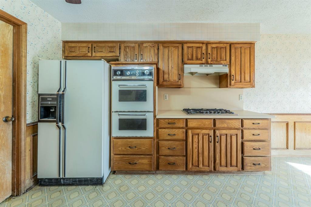 1202 Panorama Loop Waxahachie, TX 75165 - Photo 8 of 26 Kitchen featuring wallpapered walls, white refrigerator with ice dispenser, brown cabinetry, light flooring, and light countertops