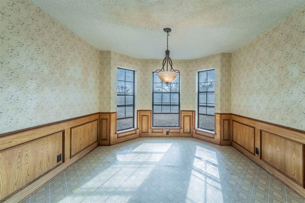 1202 Panorama Loop Waxahachie, TX 75165 - Photo 9 of 26 Unfurnished dining area with a textured ceiling, wallpapered walls, and wainscoting