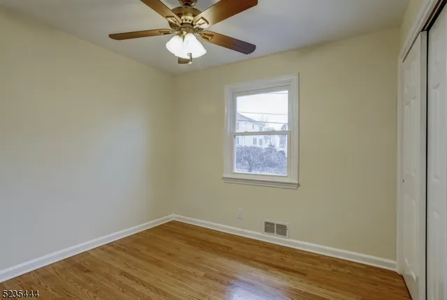 an empty room with wooden floor closet and windows
