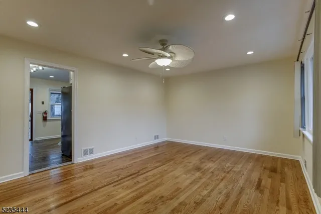 an empty room with wooden floor and a ceiling fan