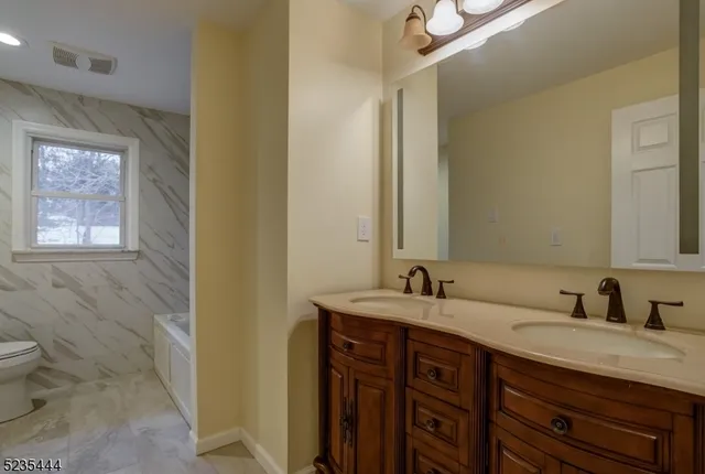 a bathroom with a double vanity sink toilet and a mirror