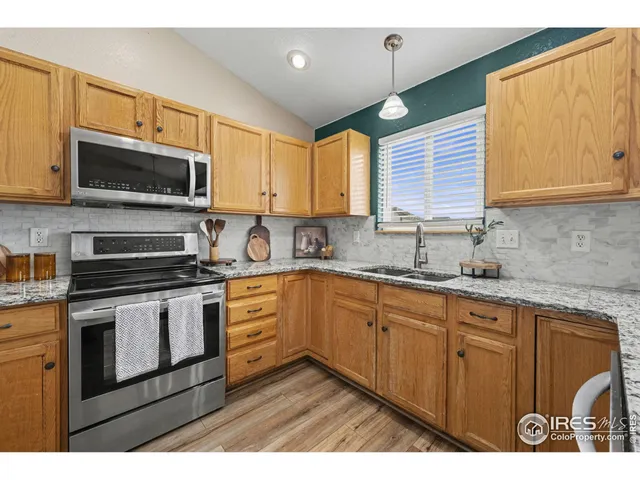 a kitchen with stainless steel appliances granite countertop a refrigerator a stove a sink and a white cabinets