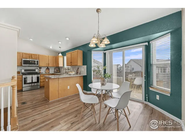 a view of a dining room with furniture a chandelier and large windows