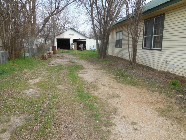 a view of a yard in front of a house with large trees