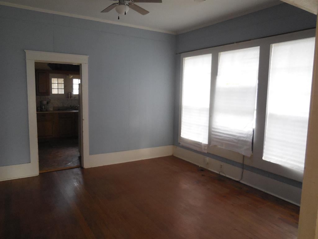910 Sinclair Street Ranger, TX 76470 - Photo 5 of 21 a view of an empty room with wooden floor and a window