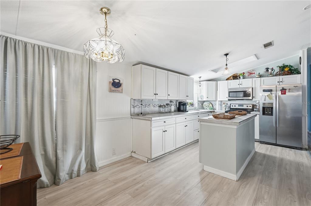1205 Calvary Road Holiday, FL 34691 - Photo 6 of 34 a kitchen with stainless steel appliances granite countertop a refrigerator a oven a sink dishwasher and white cabinets with wooden floor