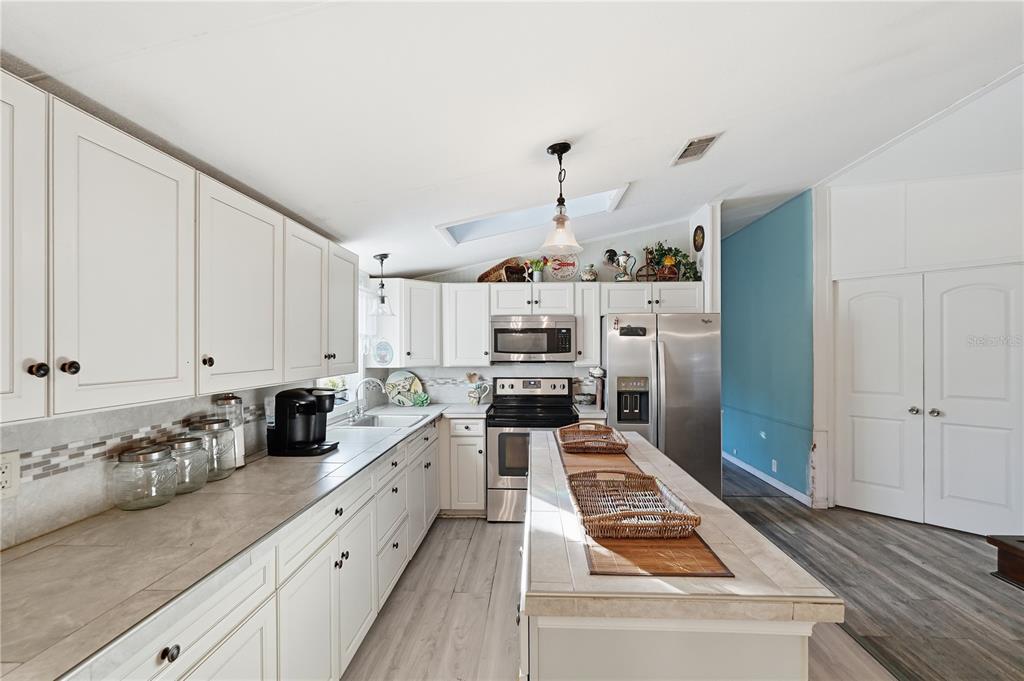 1205 Calvary Road Holiday, FL 34691 - Photo 8 of 34 a kitchen with white cabinets and appliances