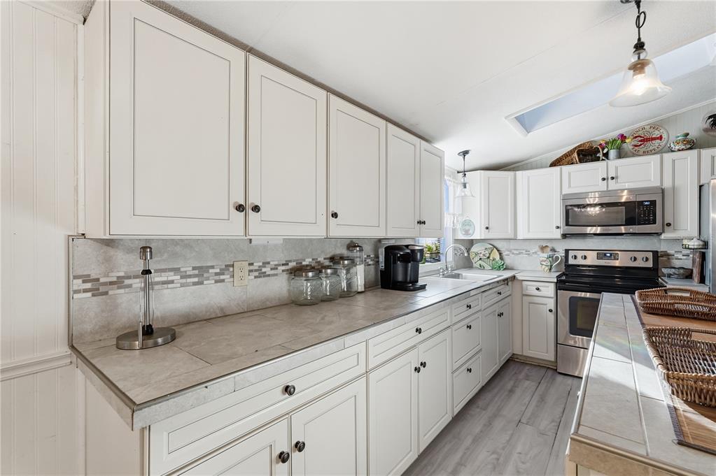 1205 Calvary Road Holiday, FL 34691 - Photo 9 of 34 a kitchen with kitchen island granite countertop a sink stainless steel appliances and white cabinets