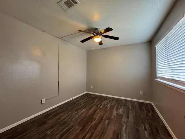 a view of room with hardwood floor and a ceiling fan