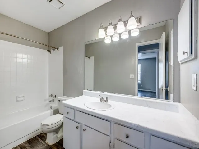 a bathroom with a sink a toilet a large mirror and shower