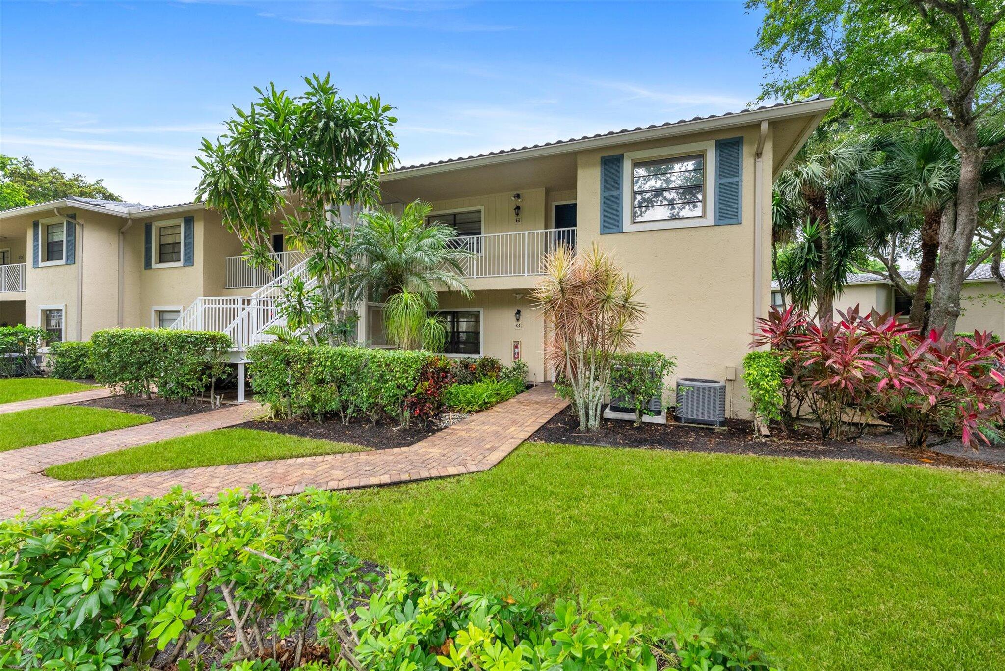 30 Westgate Lane, Unit 30G Boynton Beach, FL 33436 - Photo 28 of 58 a front view of a house with a yard and potted plants