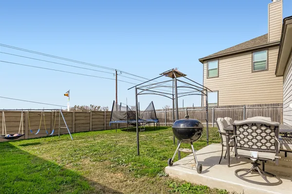 a view of a backyard with table and chairs potted plants and wooden fence