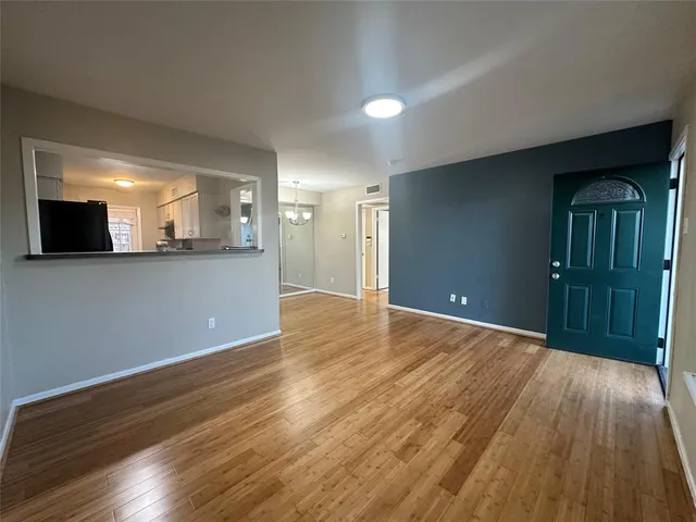 a view of a livingroom with wooden floor and a kitchen
