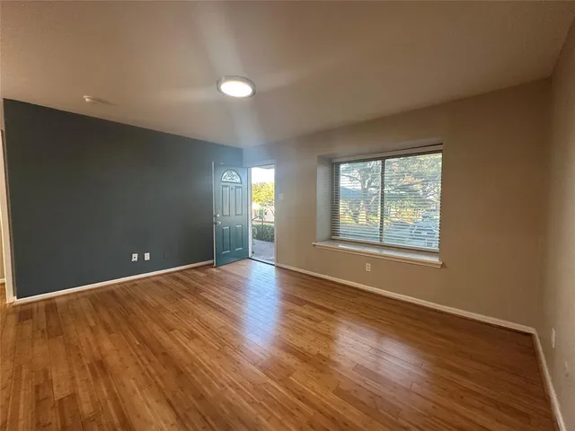 a view of an empty room with wooden floor and windows