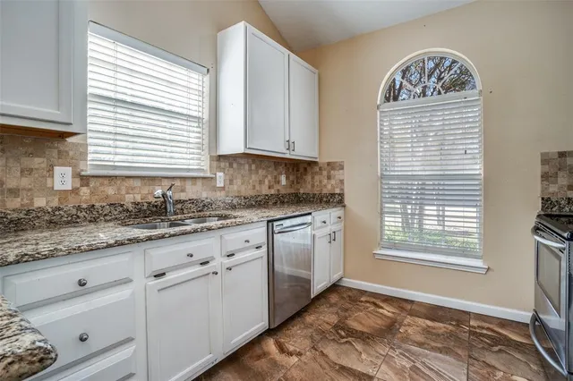 a kitchen with granite countertop stainless steel appliances granite countertop white cabinets and a window