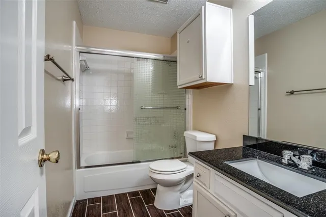 a bathroom with a granite countertop sink toilet a mirror and shower