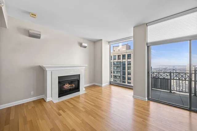 a view of an empty room with wooden floor fireplace and a window