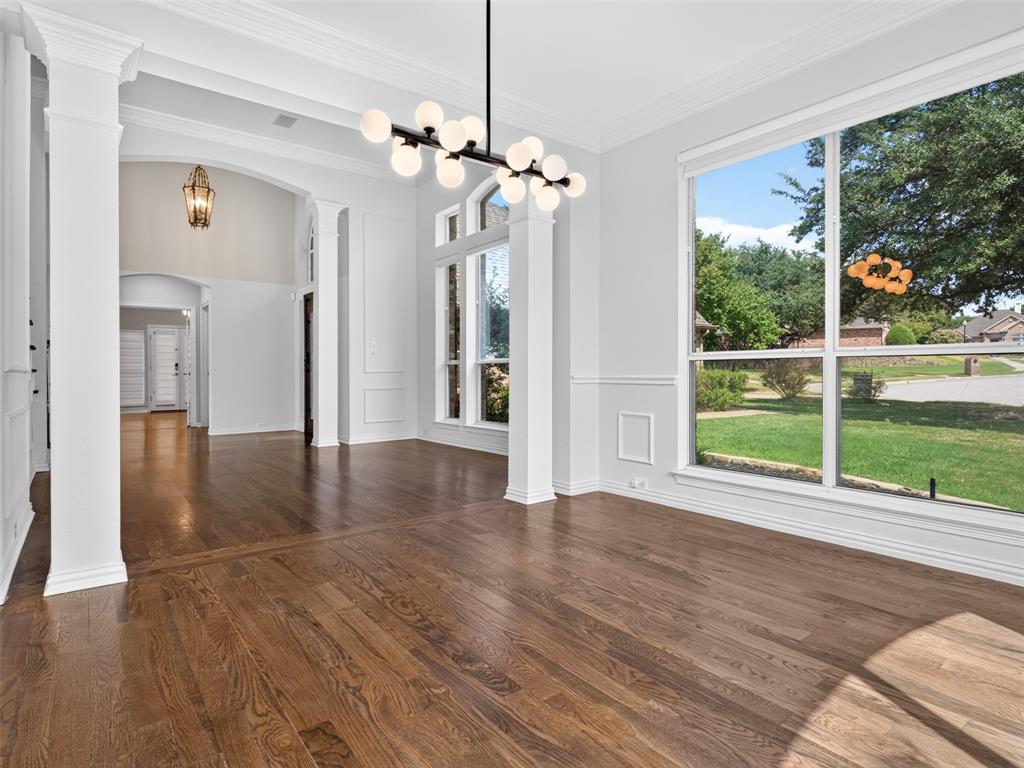 6809 Cedar Ridge Court Plano, TX 75093 - Photo 8 of 38 Spacious interior featuring wood-finish flooring, large picture windows, decorative wainscoting, and a contemporary chandelier